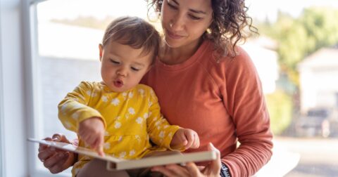 une assistante maternelle lit un livre avec un jeune enfant.