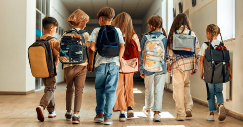Un groupe d'enfant marchent dans un couloir d'école.