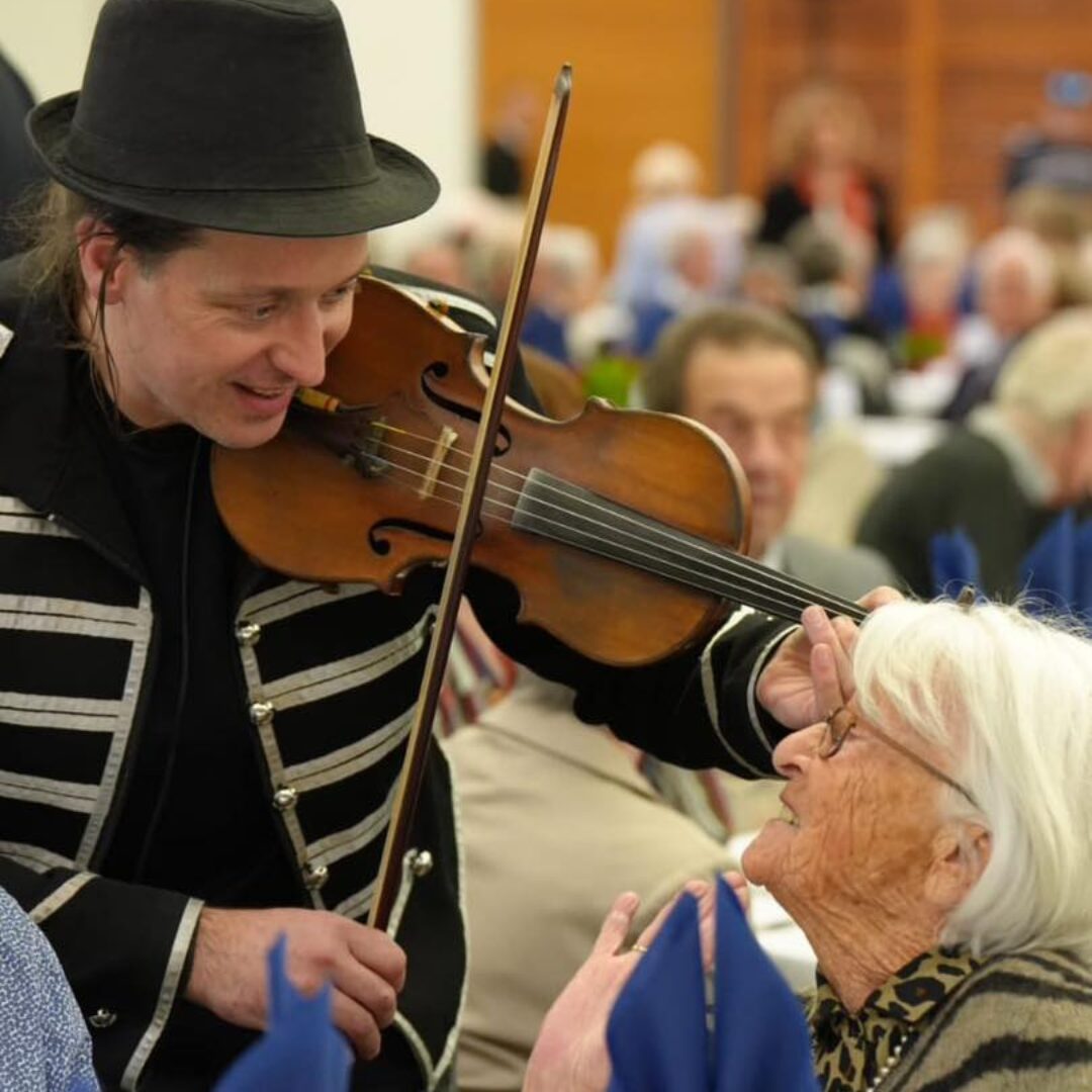 Un violoniste se produit autour des tables lors du Repas des Ainés, organisé par le Centre Communal d'Action Sociale
